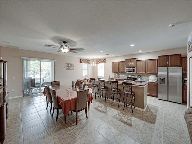 dining room with a textured ceiling, ceiling fan, and light tile patterned floors