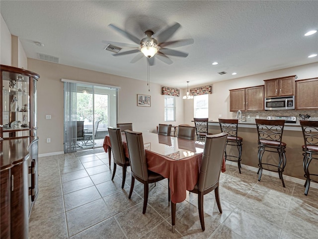 dining space with a wealth of natural light, a textured ceiling, and ceiling fan