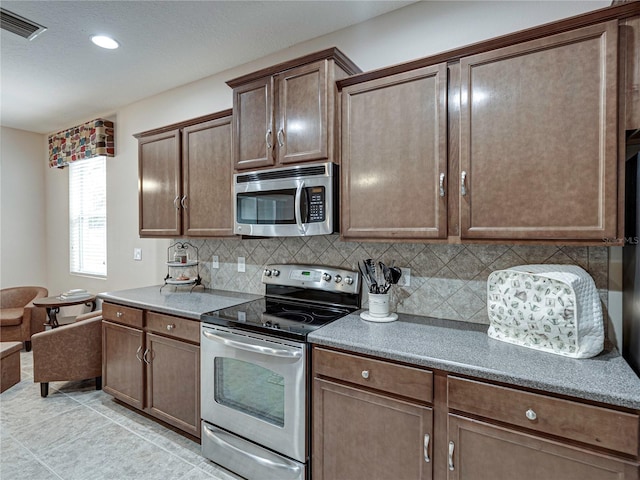 kitchen featuring stainless steel appliances, light tile patterned floors, and tasteful backsplash