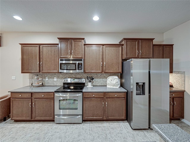 kitchen with a textured ceiling, decorative backsplash, appliances with stainless steel finishes, and light tile patterned floors