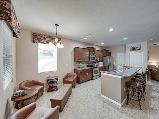 kitchen with stainless steel appliances, an inviting chandelier, decorative backsplash, hanging light fixtures, and sink