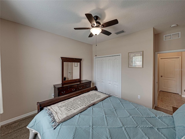 carpeted bedroom with a closet, a textured ceiling, and ceiling fan