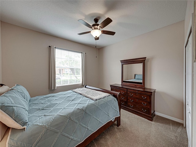 bedroom with ceiling fan, a textured ceiling, light carpet, and a closet