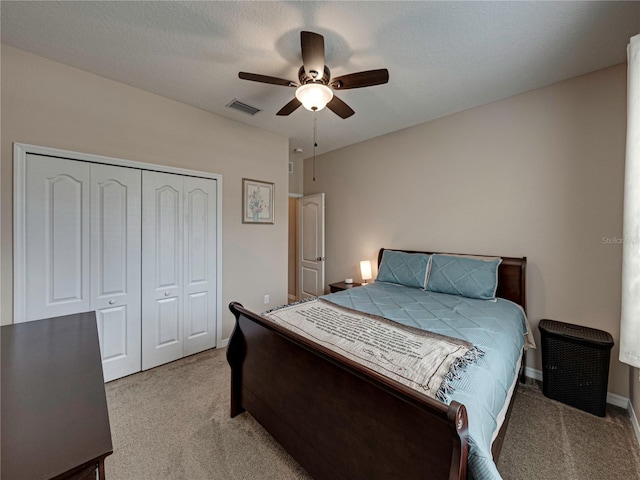 carpeted bedroom with a textured ceiling, ceiling fan, and a closet