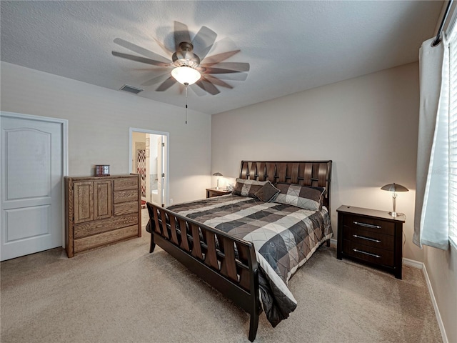 carpeted bedroom with a textured ceiling, ceiling fan, and connected bathroom