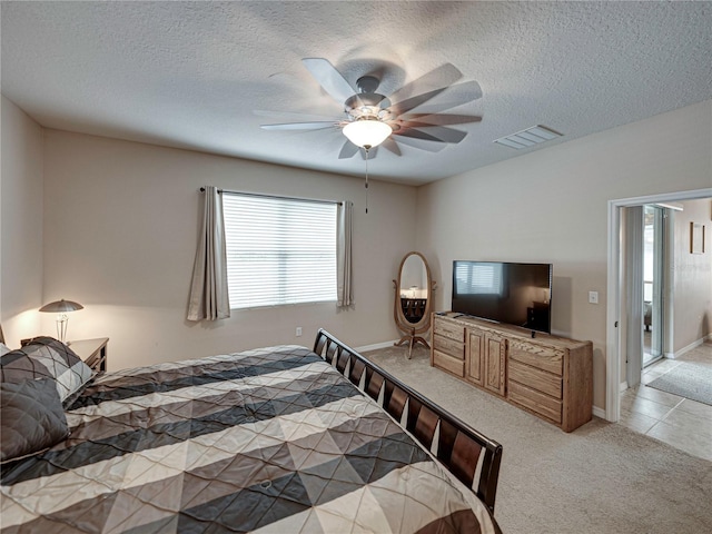 bedroom featuring a textured ceiling, light colored carpet, and ceiling fan