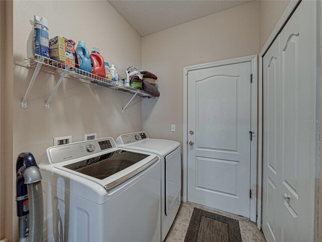 laundry room featuring washing machine and dryer, a textured ceiling, and light tile patterned flooring