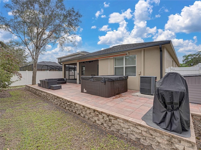 rear view of house featuring a hot tub, central AC unit, a lawn, and a patio area