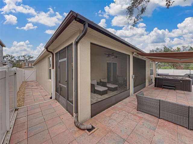 view of patio featuring a hot tub, a sunroom, and ceiling fan