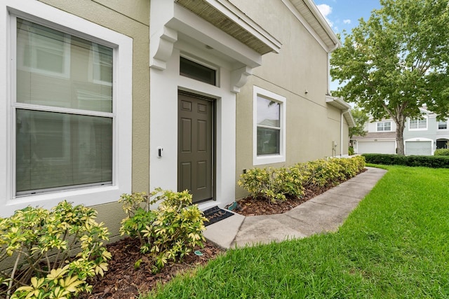 doorway to property with a garage and a lawn