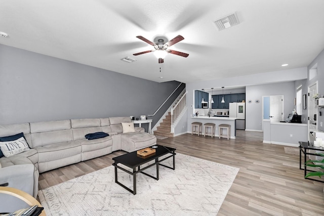 living room with light hardwood / wood-style flooring and ceiling fan