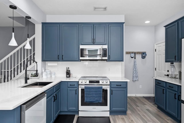 kitchen with sink, appliances with stainless steel finishes, blue cabinetry, dark wood-type flooring, and pendant lighting