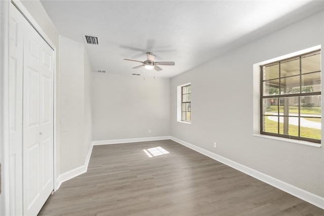 unfurnished bedroom featuring multiple windows, ceiling fan, and dark hardwood / wood-style floors