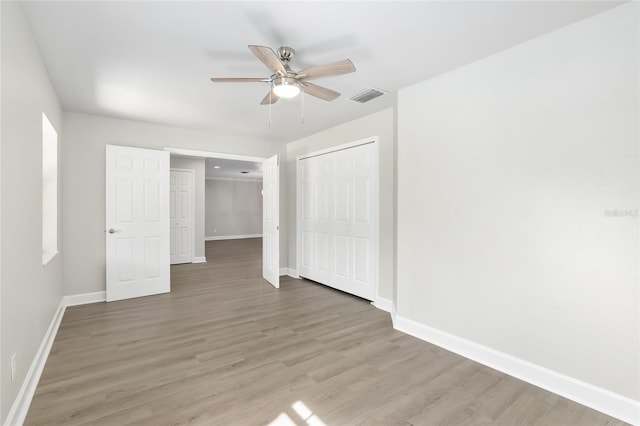 unfurnished bedroom featuring hardwood / wood-style flooring, ceiling fan, and a closet