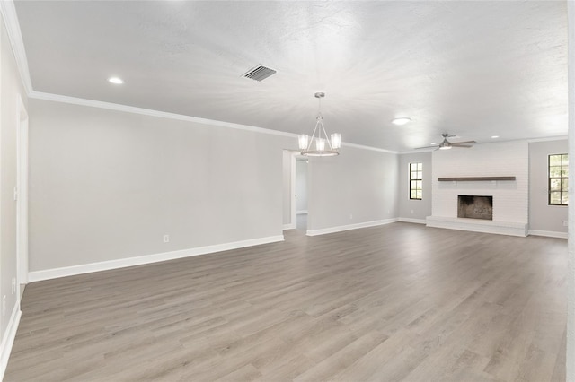 unfurnished living room featuring hardwood / wood-style floors, ceiling fan with notable chandelier, crown molding, and a fireplace