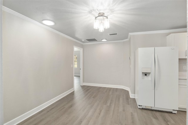 empty room featuring light wood-type flooring and ornamental molding