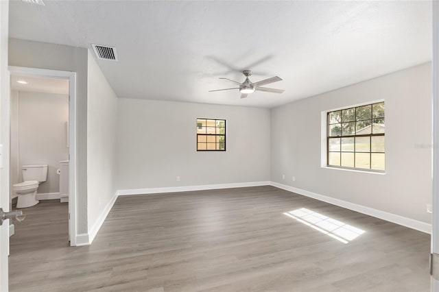 empty room featuring a wealth of natural light, hardwood / wood-style flooring, and ceiling fan