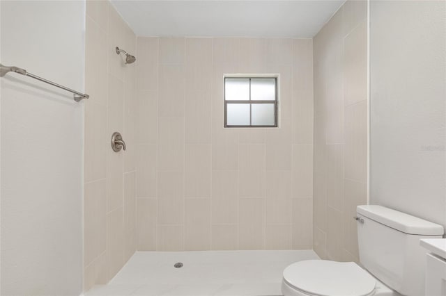 bathroom with toilet, vanity, and a tile shower