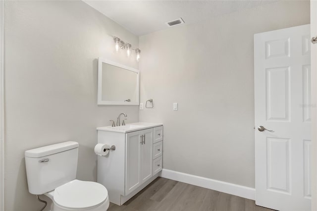 bathroom with hardwood / wood-style floors, vanity, and toilet