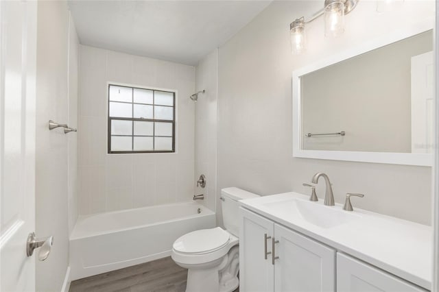 full bathroom featuring hardwood / wood-style floors, tiled shower / bath, toilet, and vanity