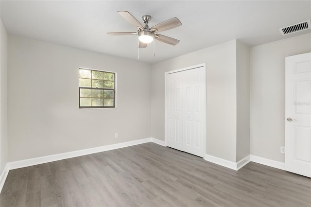 unfurnished bedroom with ceiling fan, dark hardwood / wood-style floors, and a closet