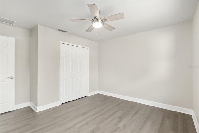 unfurnished bedroom with light hardwood / wood-style flooring, ceiling fan, and a closet