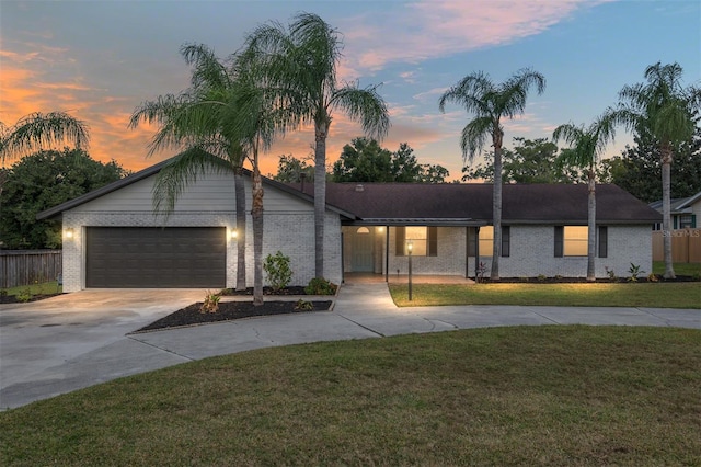 single story home featuring a garage and a yard