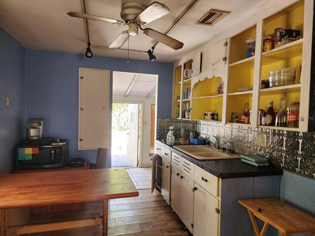 kitchen with white cabinets, wood-type flooring, sink, and backsplash