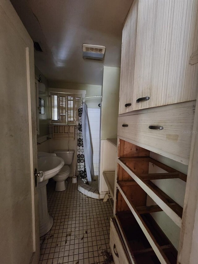 bathroom featuring a shower with shower curtain, tile patterned flooring, toilet, and tile walls