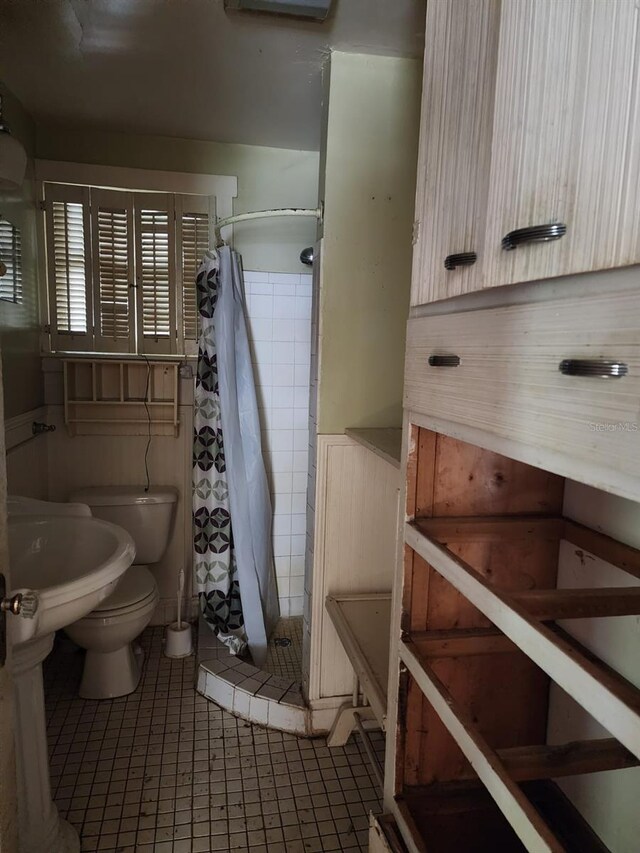 bathroom featuring walk in shower, tile patterned flooring, toilet, and tile walls