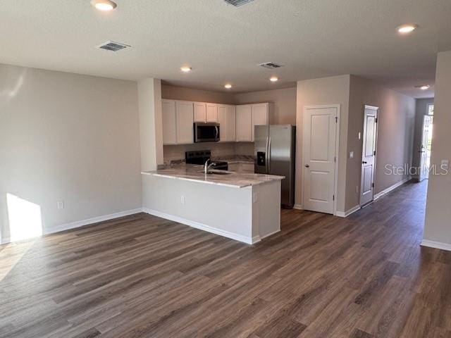 kitchen featuring sink, dark hardwood / wood-style flooring, kitchen peninsula, white cabinets, and appliances with stainless steel finishes