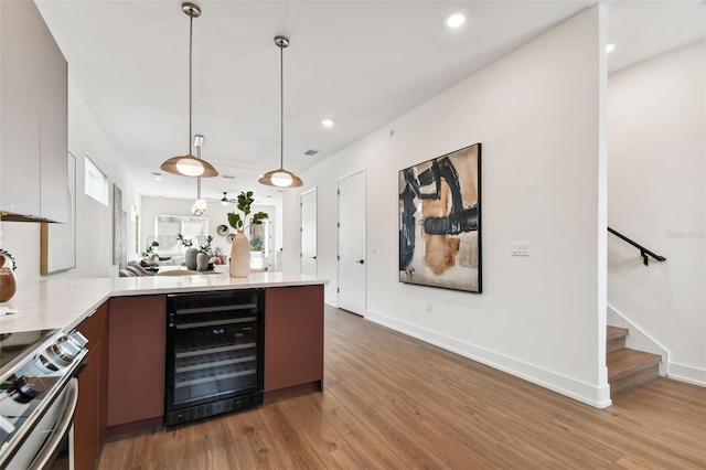 bar with beverage cooler, hanging light fixtures, hardwood / wood-style floors, and stainless steel range with electric cooktop