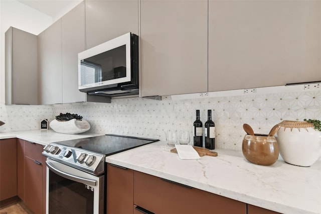 kitchen featuring stainless steel electric range oven, light stone counters, and backsplash