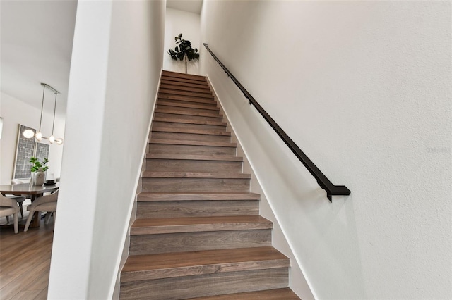 stairway with hardwood / wood-style flooring and a notable chandelier