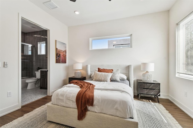 bedroom with ensuite bath, multiple windows, and dark hardwood / wood-style floors