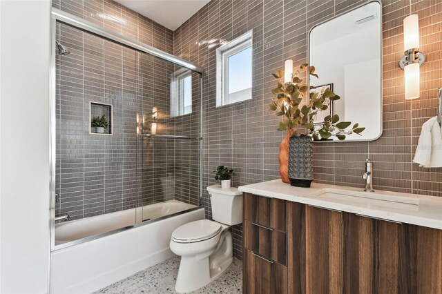 full bathroom featuring tasteful backsplash, tile walls, enclosed tub / shower combo, vanity, and toilet