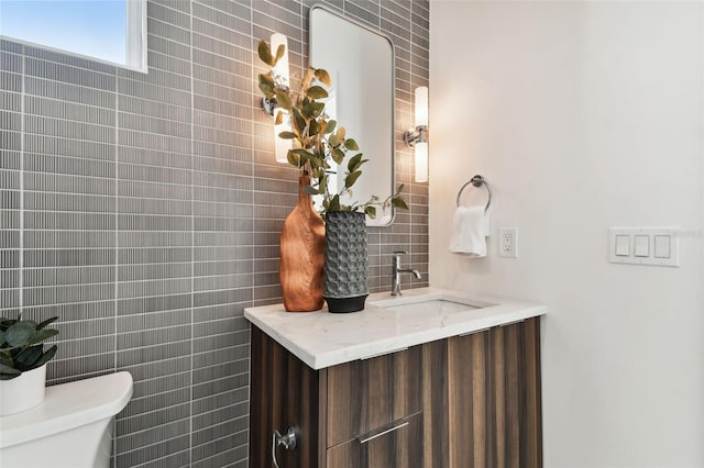 bathroom featuring vanity, toilet, and tile walls