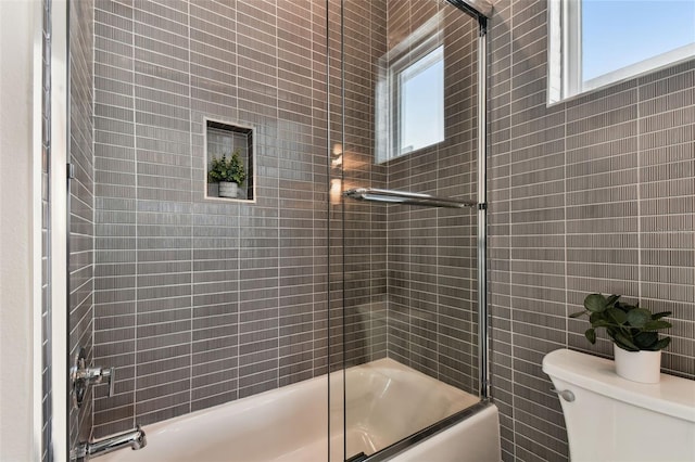 bathroom featuring plenty of natural light, shower / bath combination with glass door, and toilet