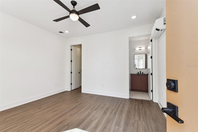 unfurnished room featuring an AC wall unit, ceiling fan, and light hardwood / wood-style flooring