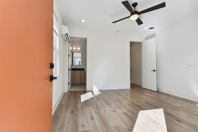 unfurnished room featuring ceiling fan, a wall mounted AC, and light hardwood / wood-style flooring