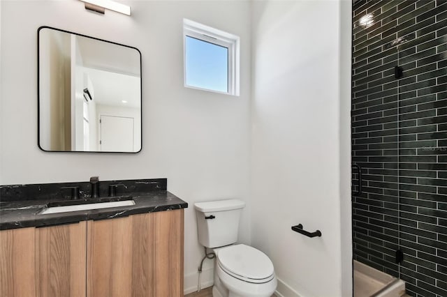 bathroom featuring tiled shower, vanity, and toilet