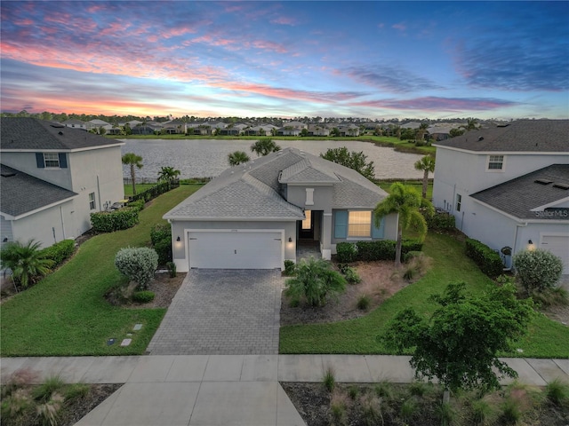 view of front of home featuring a garage, a water view, and a lawn