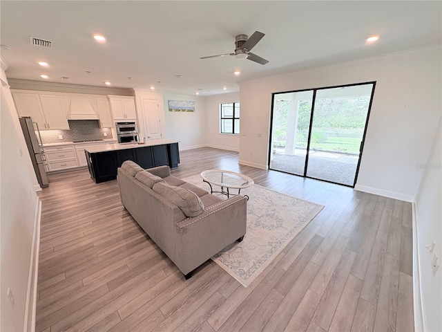 living room with light hardwood / wood-style floors, ceiling fan, and crown molding