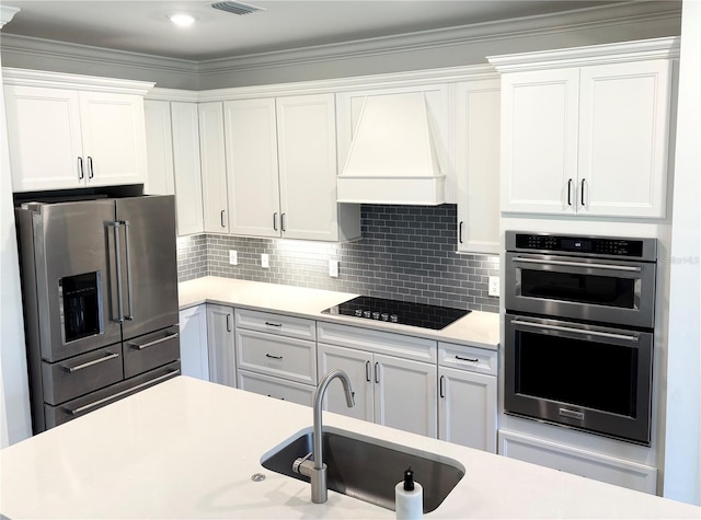 kitchen with white cabinetry, appliances with stainless steel finishes, and custom range hood