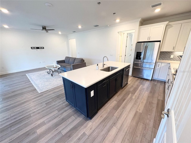 kitchen with light hardwood / wood-style floors, sink, appliances with stainless steel finishes, an island with sink, and white cabinets