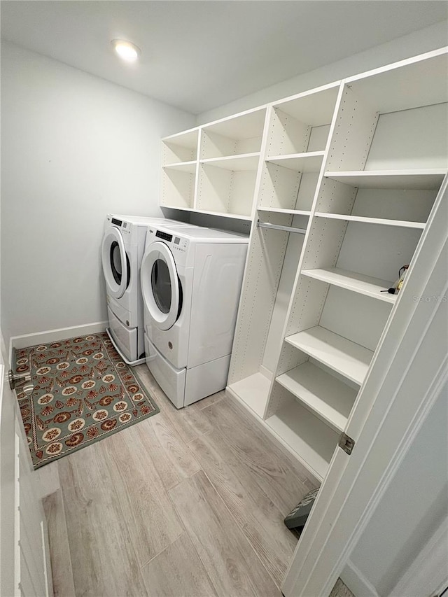 laundry area with washing machine and dryer and light hardwood / wood-style flooring