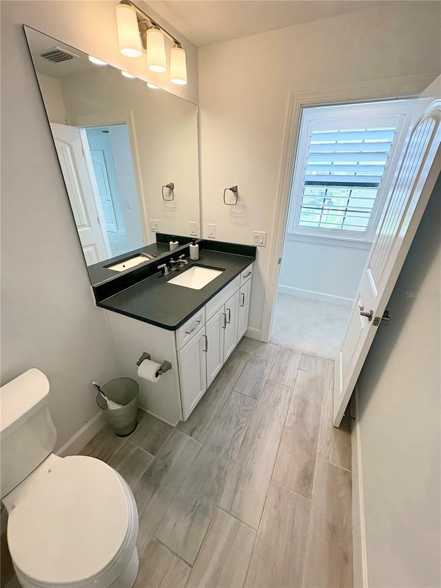 bathroom with toilet, vanity, and hardwood / wood-style flooring