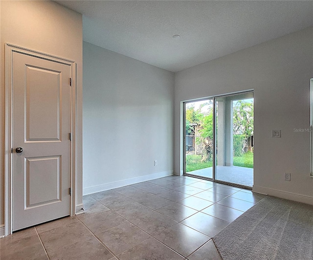 unfurnished room with a textured ceiling and light tile patterned flooring