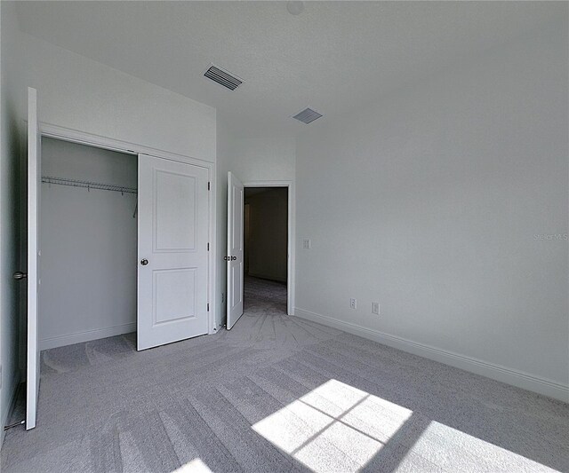 unfurnished bedroom featuring a closet and light colored carpet