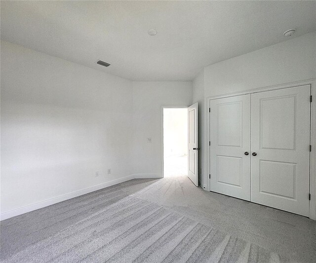 unfurnished bedroom featuring a closet and light carpet